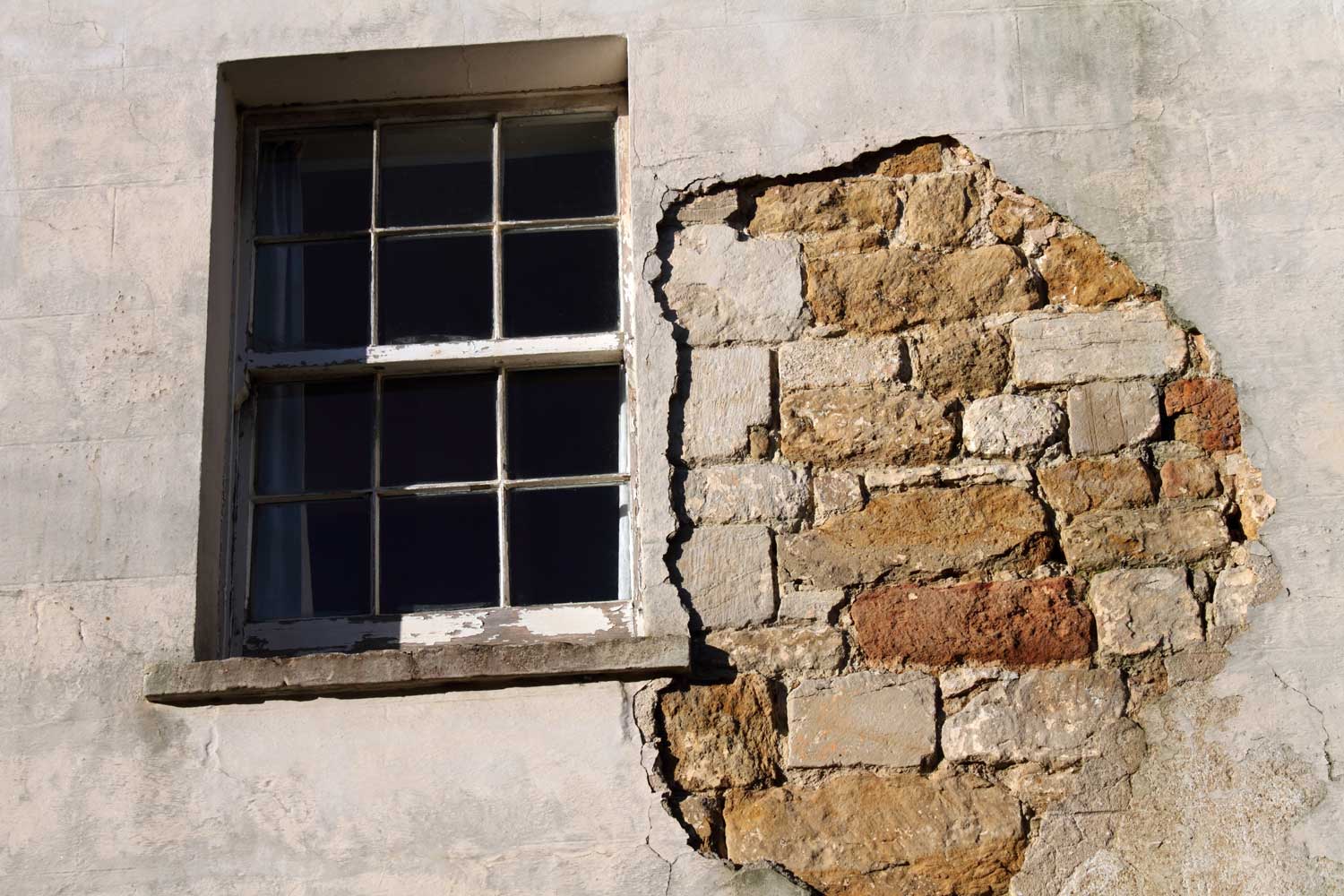 Old sash window and wall with missing render